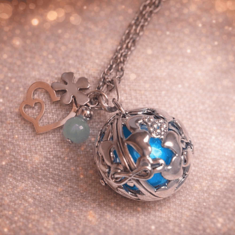 bola de grossesse personnalise Bola de grossesse en acier argenté au design ajouré, sublimé par une pierre bleue lumineuse. Son tintement doux favorise la détente et le bien-être pendant la grossesse. Accompagné de charms délicats (trèfle, cœur ou perle), ce bijou symbolise la protection, la sérénité et l’harmonie. Idéal comme cadeau de grossesse ou bijou de maternité.